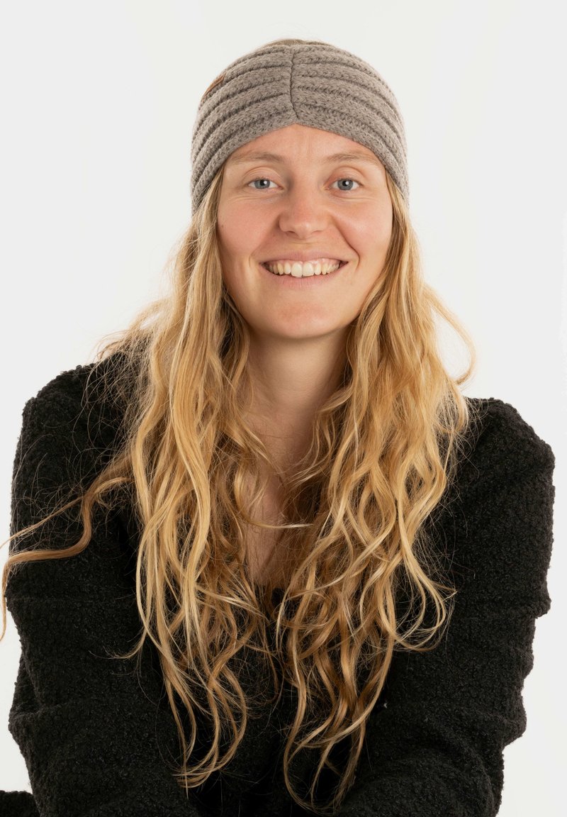 Fascia grigia a maglia con design testurizzato e righe, dotata di un piccolo tag in pelle marrone. Il modello indossa un maglione nero in pelliccia.