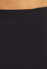 Svarta, ribbade leggings med bred midja, tillverkade av ett mjukt och elastiskt material för komfort och flexibilitet.