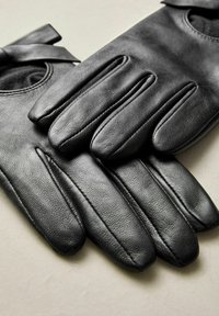 Schwarze Lederhandschuhe mit einer glatten Textur, passgenauer Form und fünf separaten Fingerabschnitten, ausgestattet mit einem kleinen Bandakzent am Handgelenk.