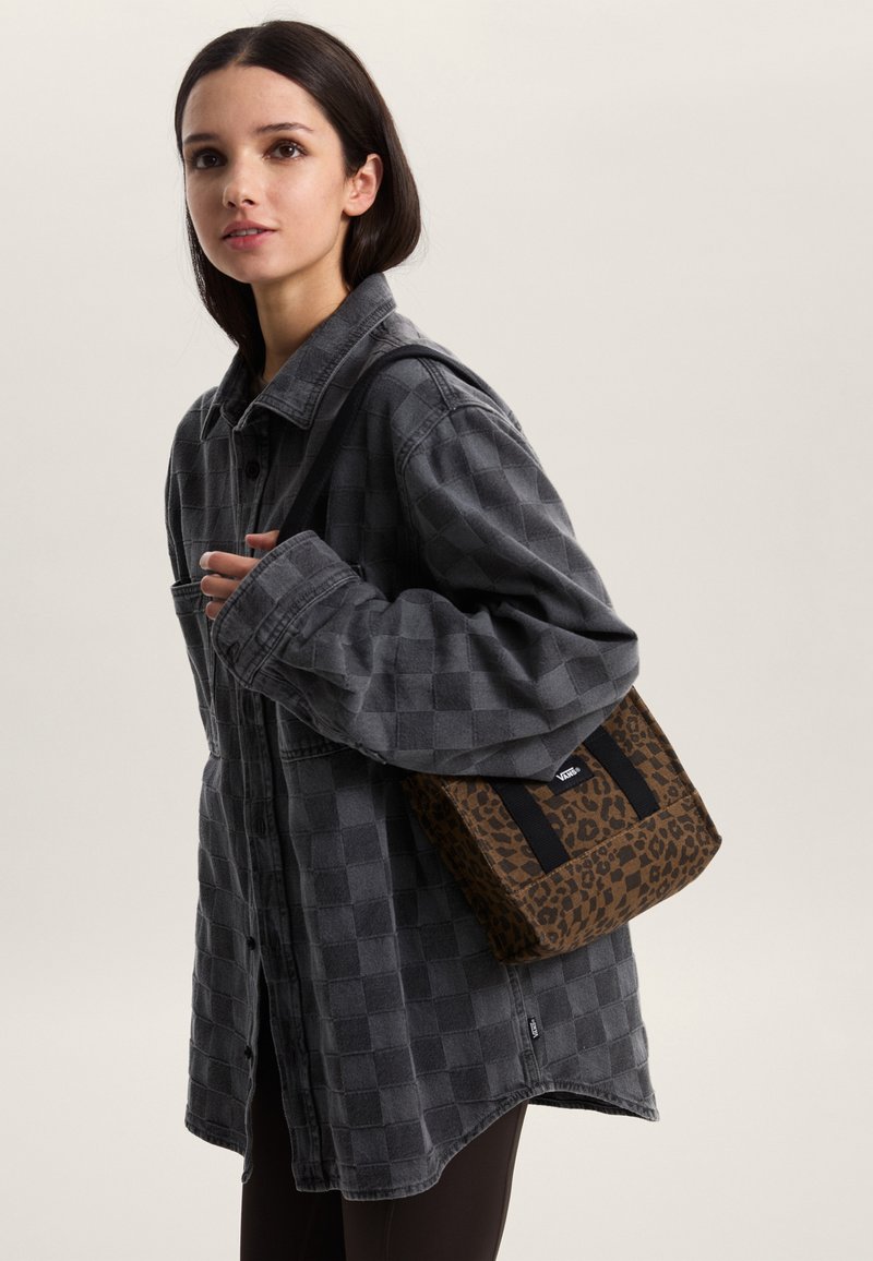 Szara koszula w kratę z zapięciem na guziki z przodu oraz brązowa torba w panterkę z czarnymi paskami i metką z logo.