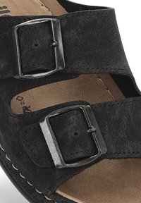 Sandal de ante negro con dos correas ajustables con hebillas plateadas, una plantilla acolchada y una suela cosida de color marrón.