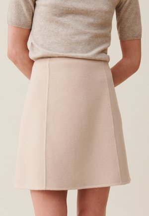 Falda de lana beige con una cintura ajustada y forma en A, que presenta detalles de costura sutiles y una tela suave y texturizada.