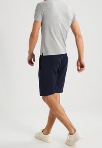 Gray short-sleeve shirt, navy shorts, and white sneakers. The shirt has a round neck and a relaxed fit. Shorts feature side pockets.