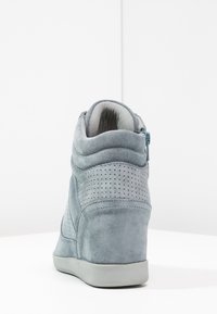 Gray suede high-top sneaker featuring a perforated design, zipper closure, textured paneling, and a rubber sole.