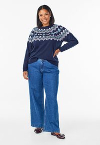 Námornícky sveter s fair isle vzorom, voľný strih. V kombinácii so širokými modrými džínsy a tmavými topánkami. Hladká látka s rebrovanými manžetami.