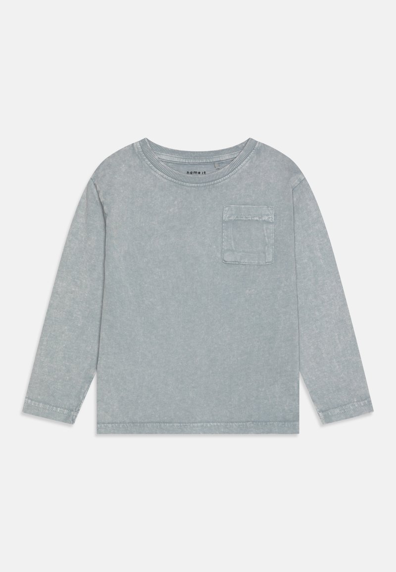 Camisa de manga larga en un tono azul claro, con cuello redondo, un bolsillo frontal y una tela texturizada con un acabado desgastado.