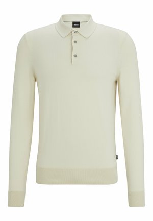 Långärmad polo i ljusbeige, med knappkrage, ribbade muddar och fåll samt en subtil textur. Märkesetikett synlig vid kragen.