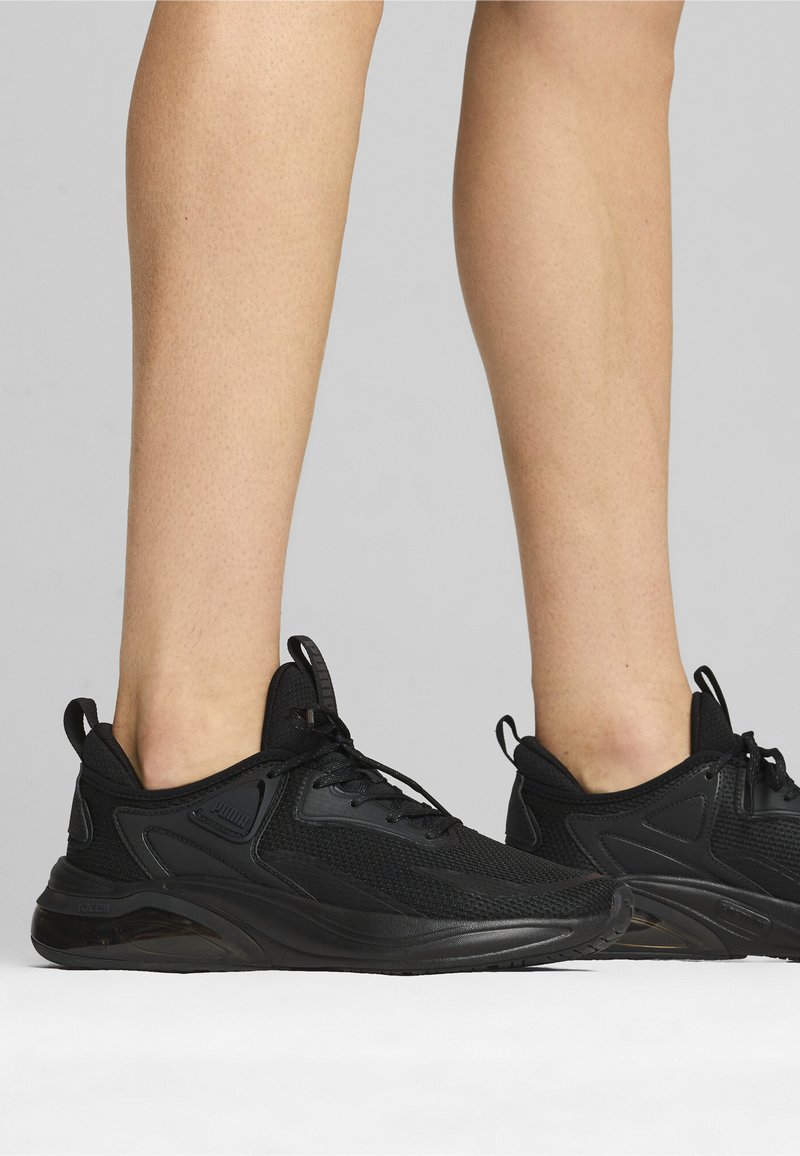 Zwarte sportieve schoenen met een bovenwerk van mesh, gestructureerde overlays, vetersluiting en een gevoerde zool voor ondersteuning en comfort.