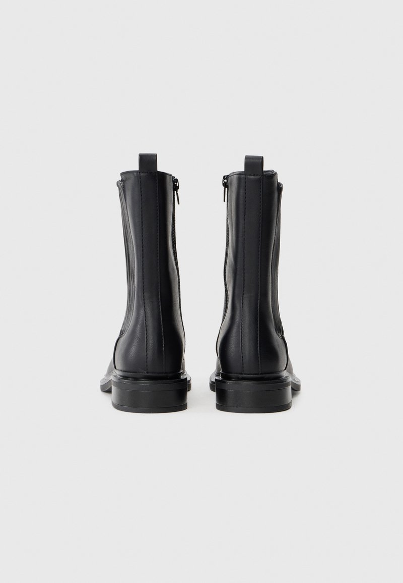 Stivali ankle in pelle nera con una texture liscia, dotati di cerniere laterali, punta arrotondata e tacco robusto. La vista posteriore mostra dettagli minimi.