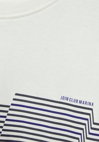 Bílá bavlněná trička s horizontálním pruhovaným vzorem v námořnické modré a modré barvě, s textem "PŘIDEJTE SE K KLUBU MARINA" napsaným malým písmem.