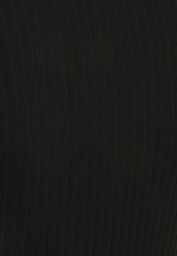 Svart ribbat tyg med vertikala linjer, som har en mjuk textur och en figurnära design. Lämpligt för olika stilar och tillfällen.