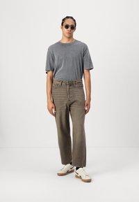 Dark gray oversized t-shirt, loose brown denim jeans, and white sneakers with brown soles, featuring a smooth texture and subtle details.