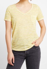 Kortemouwen gele en witte gestreepte V-hals T-shirt met een zak, gemaakt van een lichte stof, met een iets losse pasvorm en een zachte textuur.