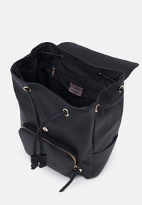 Mochila de cuero negro con cierre de cordón, acentos de hardware dorado, un bolsillo exterior con cremallera y un compartimento interior con cremallera.