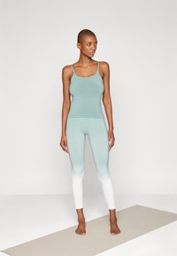 Light blue tank top with thin straps paired with light blue-to-white gradient leggings. Soft fabric with a smooth texture, suitable for activewear.