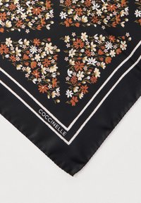 Lenço de seda com padrão floral em tons de vermelho, branco e amarelo sobre um fundo preto, com o logótipo Coccinelle delimitado a branco.