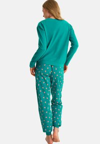 Sweatshirt teal et pantalon de pyjama avec un motif de renard. Les pantalons comportent des poignets élastiques. Le matériau semble doux et confortable. Vue arrière montrée.