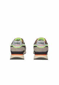 Sportieve schoenen, grijze suède en mesh bovenkant, neon groene accenten, oranje heel tab, zwarte details en het nummer "1985" op de hiel.