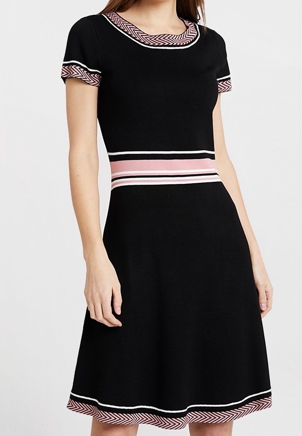 Robe noire à manches courtes avec des détails rayés roses et blancs sur le col, les manches, la taille et l'ourlet portée par une personne debout.