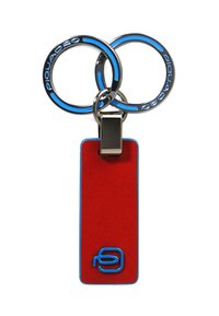 Sleutelhanger met twee zilveren ringen en een rood label. Het label heeft een blauwe rand en onderaan is de letter 'P' blauw geprint.