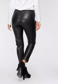 Svarta leggings i konstläder med en åtsittande design, elastiskt midjeband och slät yta. Kända med svarta ankelstövlar med hög klack.