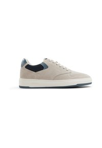 Beige suede sneaker with a textured navy fabric accent, white midsole, and light blue rubber outsole. Features round laces and eyelet detailing.
