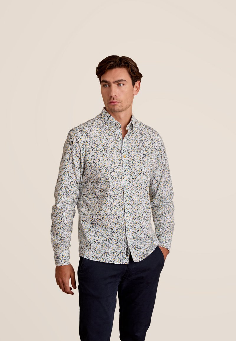 Overhemd met knoopsluiting op een witte basis, voorzien van een kleurrijk bloemenpatroon. Gemaakt van stof met een gladde textuur en een klassiek kraagontwerp.
