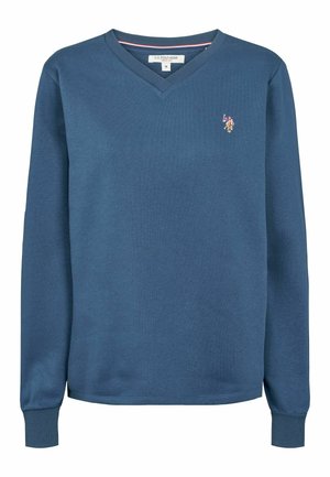 Mėlynas v-kaklo džemperis, pagamintas iš minkštos medžiagos, su ilgomis rankovėmis ir maža išsiuvinėta logo ant krūtinės.