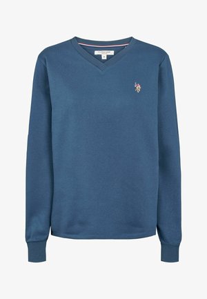 Mėlynas v-kaklo džemperis, pagamintas iš minkštos medžiagos, su ilgomis rankovėmis ir maža išsiuvinėta logo ant krūtinės.