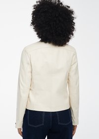 Giacca in pelle crema con un design aderente, spalle strutturate e maniche lunghe. Presenta cuciture a vista e una lunghezza cropped.
