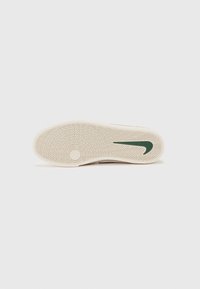 Talpa de adidasi Nike in bej cu un model de tread in zigzag. Are un logo Nike swoosh verde; textura neteda cu material din cauciuc.
