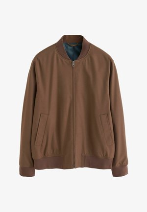 Barna bomberdzseki puha anyagból, elöl cipzárral, bordázott mandzsettákkal és két oldalsó zsebbel. A belső része kontrasztos kék bélésű.