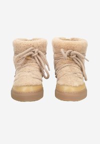 Bottes en fausse fourrure beige avec un extérieur texturé, un bout rond et de grosses lacets beiges. Les semelles en caoutchouc offrent stabilité et traction.