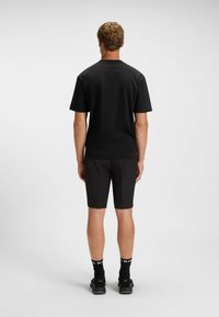 Czarny t-shirt z krótkim rękawem i pasujące szorty, wykonane z gładkiego materiału. Posiada okrągły dekolt i minimalistyczny design.