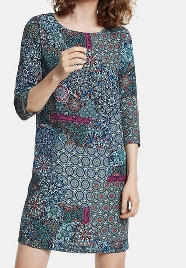 Robe multicolore avec un col rond et des manches trois-quarts. Le tissu présente des motifs élaborés dans des tons de bleu, rouge et violet.