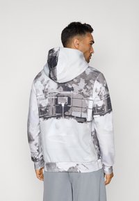Hættepullover sweatshirt i grå og hvid med et abstrakt mønster. Har ribbede manchetter og kant, glat tekstur og kængurulomme.