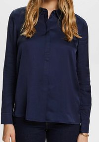 Mörkblå, knapp-up blus med långa ärmar, tillverkad av slät tyg, med en liten krage och minimalistisk design. Regular fit.