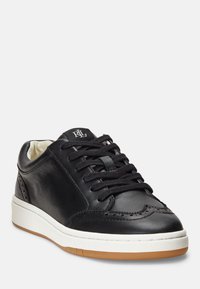 Black leather sneaker with rounded toe, white midsole, and gum outsole. Features black laces and decorative perforated design on the side.