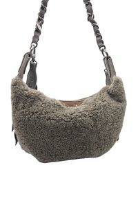 Sac d'épaule en fausse fourrure grise avec une forme incurvée, des accents en cuir et une bandoulière chaîne. Caractérisé par une surface douce et texturée ainsi qu'une fermeture éclair.