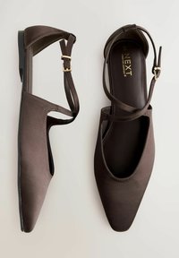 Ballerines en satin marron avec un bout pointu, des côtés ouverts, un design à lanières croisées et une petite boucle à la cheville. Texture lisse et matériel minimal.