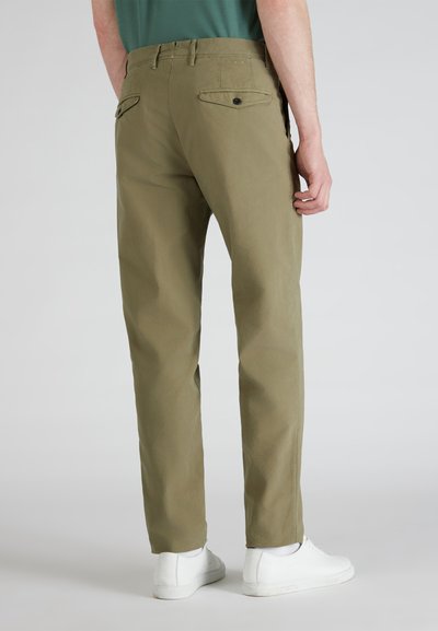 Khaki chinos met een rechte pasvorm, voorzien van twee achterzakken met knoopsluitingen, gedragen met witte sneakers, van een soepele katoenstof.