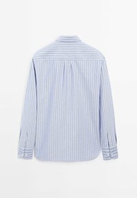 Jasnoniebieska koszula zapinana na guziki z białymi pionowymi paskami, z długimi rękawami i klasycznym kołnierzykiem. Ma plisę z tyłu i guziki przy mankietach.