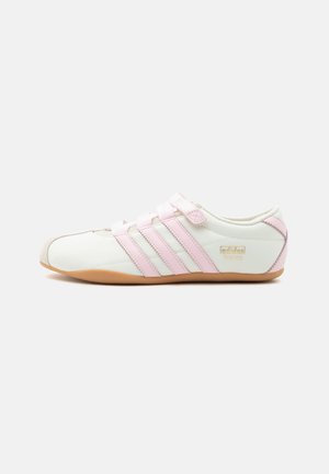 Biało-różowe buty sportowe Adidas Tokyo z trzema różowymi paskami, paskiem na rzep i gumową podeszwą na jednolitym tle.