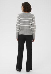 Gray knitted sweater with white stripes, ribbed hem, and long sleeves paired with black wide-leg trousers. Plain background.