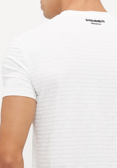 Fehér, testhez álló póló, finom tónusú, ismétlődő "DSQUARED2" mintával. Rövid ujjú és kerek nyaknál végződik, hátul a márkázás látható.