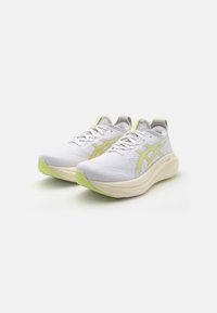 White athletic shoes with a textured upper, yellow accents, and a thick, light-colored sole. Features laces and a padded collar.