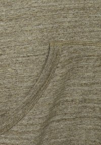 Tessuto in misto cotone di colore verde oliva spento con una superficie texturizzata. Presenta una tasca circolare con cuciture visibili lungo il bordo.