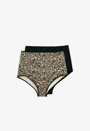 Mujer embarazada con ropa interior premamá de estampado de leopardo y cárdigan negro, posando con la mano en el cuello sobre un fondo liso.