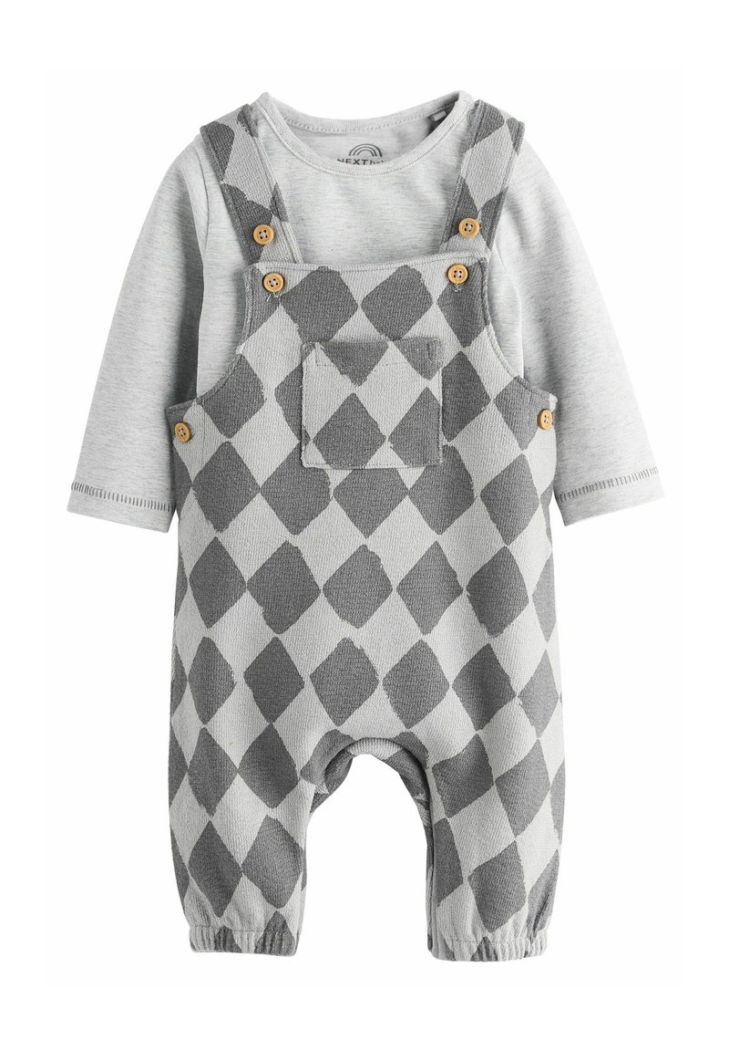 Grijs en lichtgrijs overall met ruitjespatroon, voorzien van houten knopen, een borstzak en elastische manchetten. Lange mouwen shirt eronder.