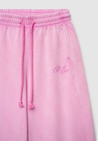 Pantalon de survêtement rose avec taille à cordon, doté d'une texture douce et du texte "Sois si mignon" brodé dans une nuance de rose assortie.